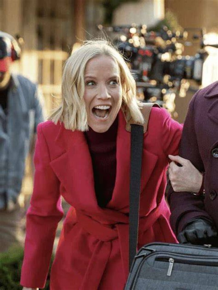 Jessy Schram in a red bodycon and black leather jacket holding a guitar and singing.